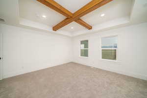 Carpeted spare room with beam ceiling