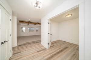 Hall with beamed ceiling, light wood-type flooring, and a chandelier