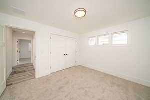 Unfurnished bedroom featuring light carpet and a closet