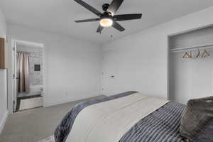 Carpeted bedroom featuring ensuite bath, ceiling fan, and a closet