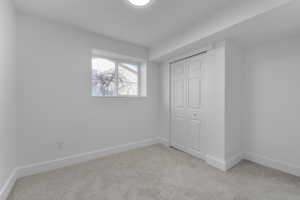 Unfurnished bedroom featuring a closet and light colored carpet