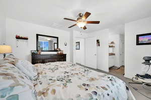 Carpeted bedroom featuring ceiling fan and ensuite bath