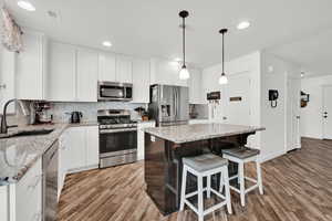 Kitchen with appliances with stainless steel finishes, a center island, light hardwood / wood-style floors, and sink