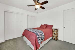 Carpeted bedroom featuring multiple closets and ceiling fan