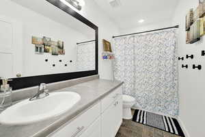 Bathroom with a shower with shower curtain, vanity, and toilet