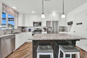 Kitchen with a breakfast bar area, light hardwood / wood-style flooring, a kitchen island, and stainless steel appliances