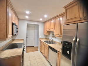 Kitchen with light wood-type flooring, sink, and appliances with stainless steel finishes