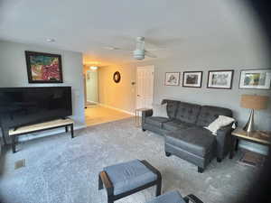 Living room with carpet flooring, ceiling fan, and a textured ceiling