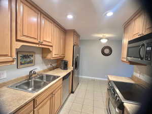 Kitchen featuring sink, light tile patterned floors, and stainless steel appliances