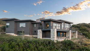 Back house at dusk with a patio area and a balcony