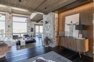 Living room featuring beamed ceiling, plenty of natural light, dark wood-type flooring, and wood ceiling