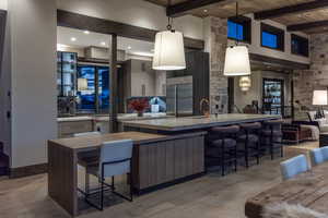 Kitchen with a kitchen breakfast bar, light wood-type flooring, beam ceiling, decorative light fixtures, and built in refrigerator