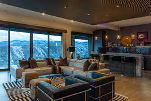 Living room featuring a mountain view, a healthy amount of sunlight, wood-type flooring, and indoor bar