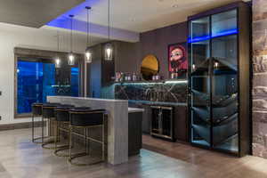 Bar with decorative backsplash, sink, decorative light fixtures, hardwood / wood-style floors, and wine cooler