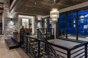 Staircase with hardwood / wood-style floors, wood ceiling, and a notable chandelier