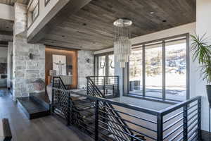 Stairway featuring hardwood / wood-style floors, a notable chandelier, and wood ceiling