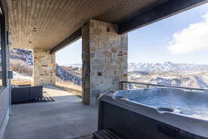 Snow covered patio with a mountain view and a hot tub