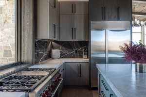 Kitchen with decorative backsplash, gray cabinets, plenty of natural light, and high quality appliances