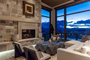 Living room with an outdoor stone fireplace, a mountain view, and a towering ceiling