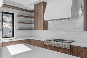 Kitchen featuring premium built in range and custom hood, tasteful backsplash, and sink with the best RO drinking water.