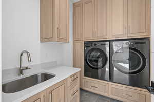 Upstairs laundry room featuring separate washer and dryer, sink, cabinets, and dark tile patterned flooring