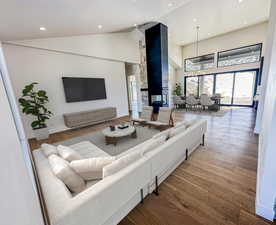 Living area with recessed lighting, high vaulted ceiling, baseboards, and wood finished floors