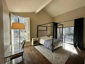 Bedroom featuring wood-type flooring, lofted ceiling with beams, access to outside, and multiple windows