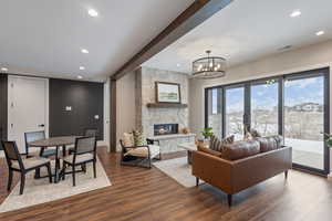 Living room with hardwood / wood-style floors, beam ceiling, a fireplace, and an inviting chandelier