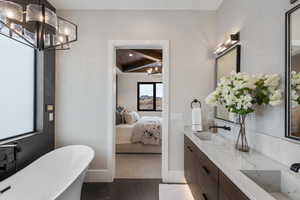 Bathroom with vanity, an inviting chandelier, tile patterned floors, beamed ceiling, and a tub