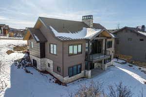 Snow covered back of property with a balcony