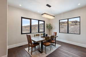 Dining room with dark wood-type flooring and a notable chandelier