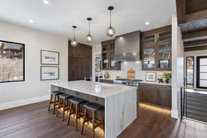 Kitchen featuring dark hardwood / wood-style flooring, stainless steel range, wall chimney range hood, and sink