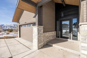 Snow covered property entrance with a mountain view and a garage