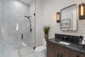 Bathroom with decorative backsplash, vanity, toilet, and an enclosed shower