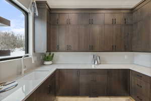 Kitchen with dark brown cabinetry, light stone counters, and a wealth of natural light