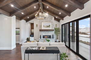 Living room featuring a mountain view, beam ceiling, dark hardwood / wood-style flooring, and wooden ceiling