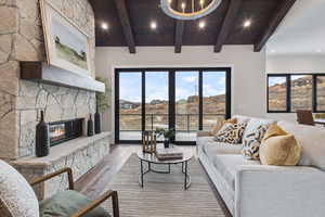 Living room featuring a stone fireplace, a wealth of natural light, wooden ceiling, and hardwood / wood-style flooring