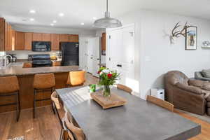 Kitchen featuring black appliances, light hardwood / wood-style floors, sink, and pendant lighting