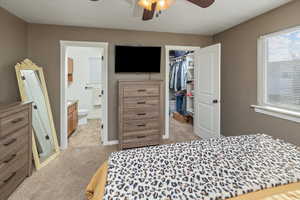 Carpeted bedroom featuring ceiling fan, a spacious closet, a textured ceiling, connected bathroom, and a closet