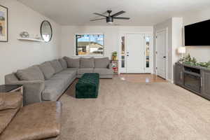 Carpeted living room featuring ceiling fan and a textured ceiling