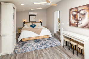 Bedroom with ceiling fan, light hardwood / wood-style floors, lofted ceiling, and an AC wall unit