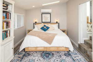 Bedroom featuring wood-type flooring, vaulted ceiling, and an AC wall unit