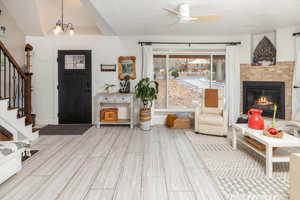 Entryway featuring a fireplace, ceiling fan with notable chandelier, and light hardwood / wood-style flooring