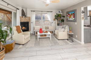 Living room with a brick fireplace, ceiling fan, and light wood-type flooring