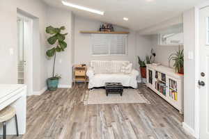 Living area with hardwood / wood-style floors and vaulted ceiling