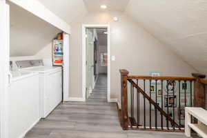 Laundry room with hardwood / wood-style floors, a textured ceiling, and washer and clothes dryer