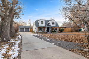 Cape cod home with an outbuilding, a garage, and covered porch