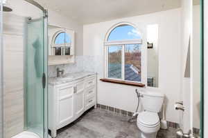 Bathroom featuring decorative backsplash, a shower, vanity, and toilet