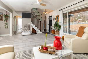 Living room featuring vaulted ceiling, light hardwood / wood-style flooring, and ceiling fan with notable chandelier