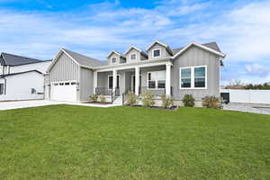 View of front of property featuring a porch, a garage, and a front lawn